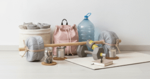 Academia em casa com pesos improvisados feitos com almofadas, garrafa de água, halteres e mochila sobre um tapete.