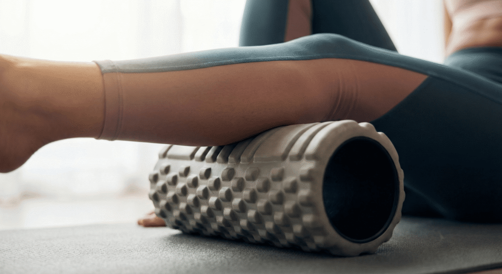 Pessoa usando rolo de liberação miofascial (foam roller) para aliviar a dor muscular.