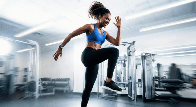 Mulher fazendo agachamento com salto durante circuito HIIT na academia.