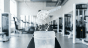 Scoop com pó de creatina sendo colocado em uma coqueteleira na academia. O fundo da imagem precisa ser “clean”.