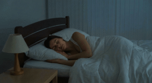 Mulher dormindo profundamente em um quarto escuro e confortável praticando higiene do sono.