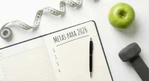 Caderno de planejamento aberto em uma mesa com fita métrica e haltere, simbolizando metas fitness de ano novo.